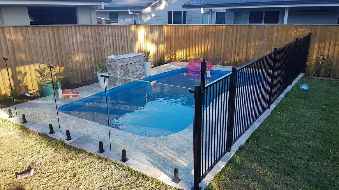 Swimming pool enclosed by glass and black metal fencing